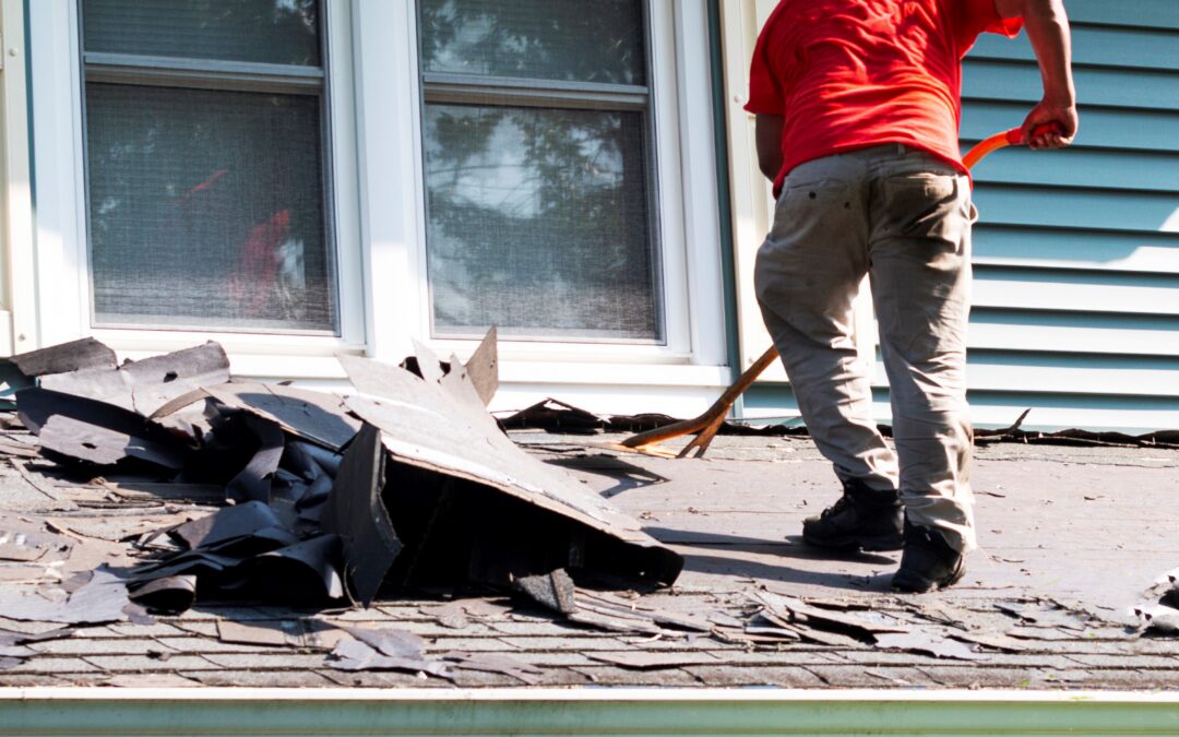 Man standing on a residential homes roof removing the shingles.