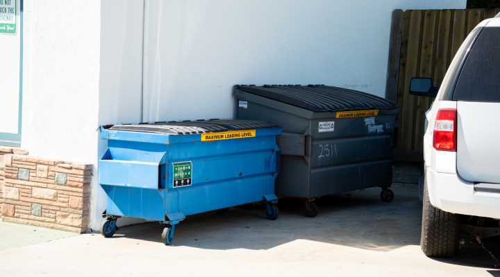 Two dumpster rentals for residential building parked against a white wall.