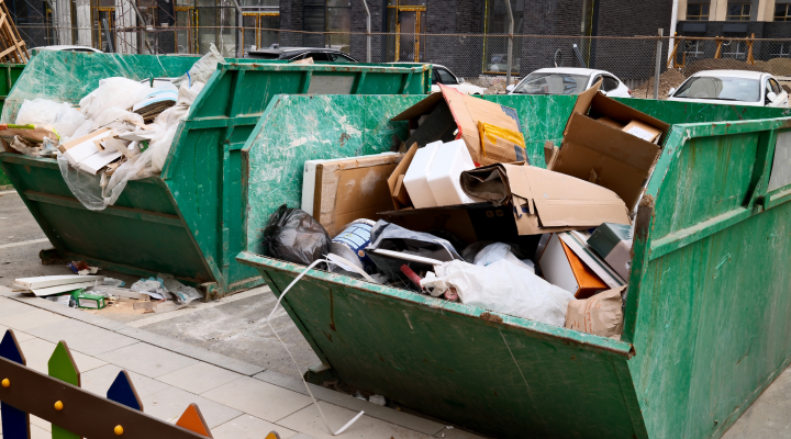 Two green dumpsters with various materials from a construction project sorted into them.